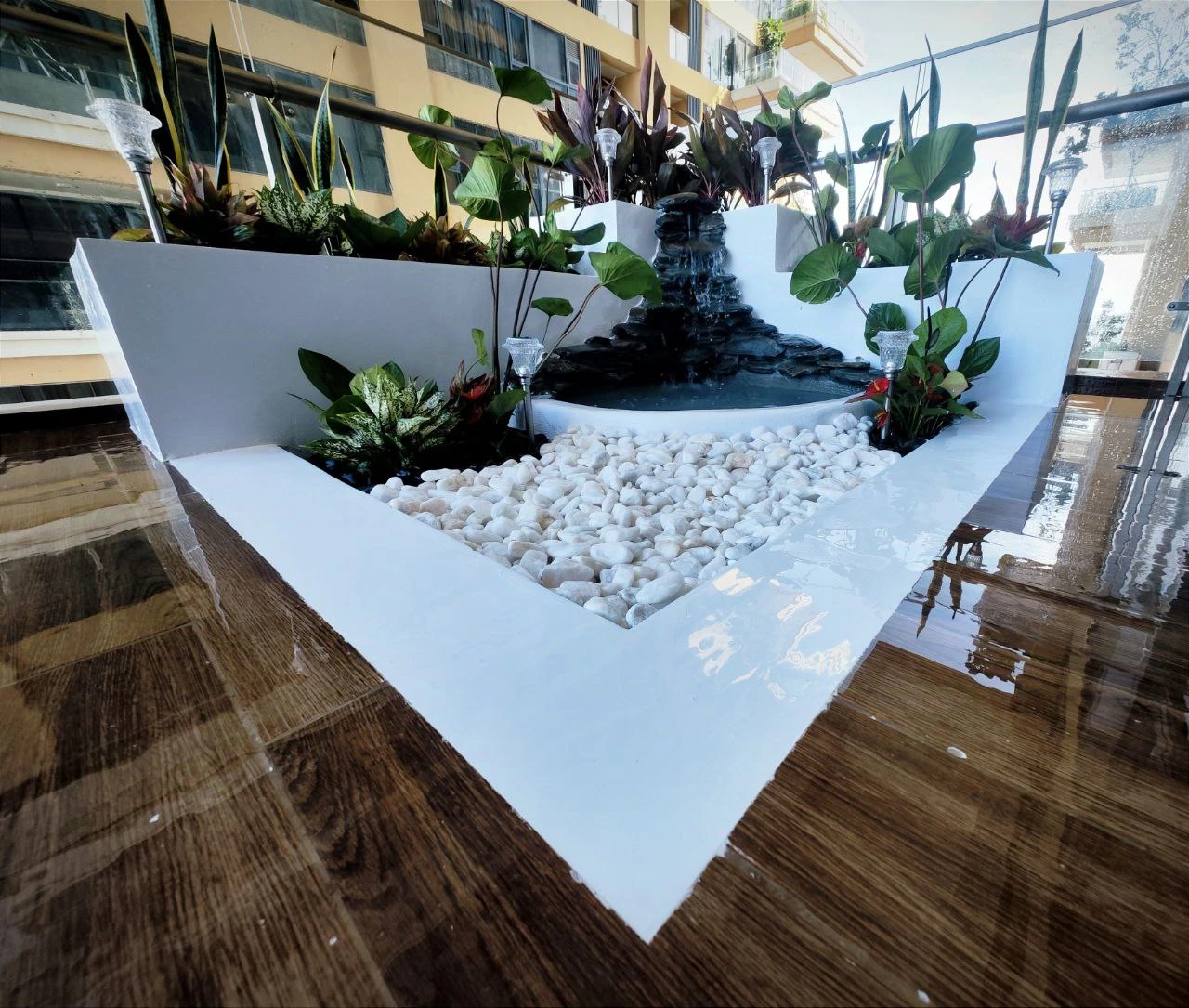 Bespoke corner balcony koi pond installation with white pebble hardscaping in Phnom Penh